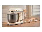Retro-style cream stand mixer with a stainless steel bowl on a wooden kitchen countertop.