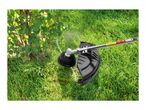 A grass trimmer cutting grass around a bush, with a protective shield visible.