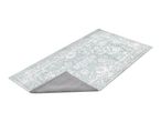 Light blue patterned rug with a non-slip backing shown folded over at one corner