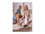 Two people in casual wear, wearing clogs, crouching on a tiled floor.