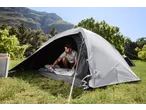 Man in CRIVIT 4 Person Blackout Tent, setting up sleeping bag, mountains in background.