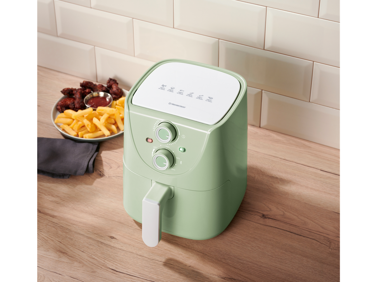 Svijetlozeleni air fryer SilverCrest s pomfritom i pilećim krilima.