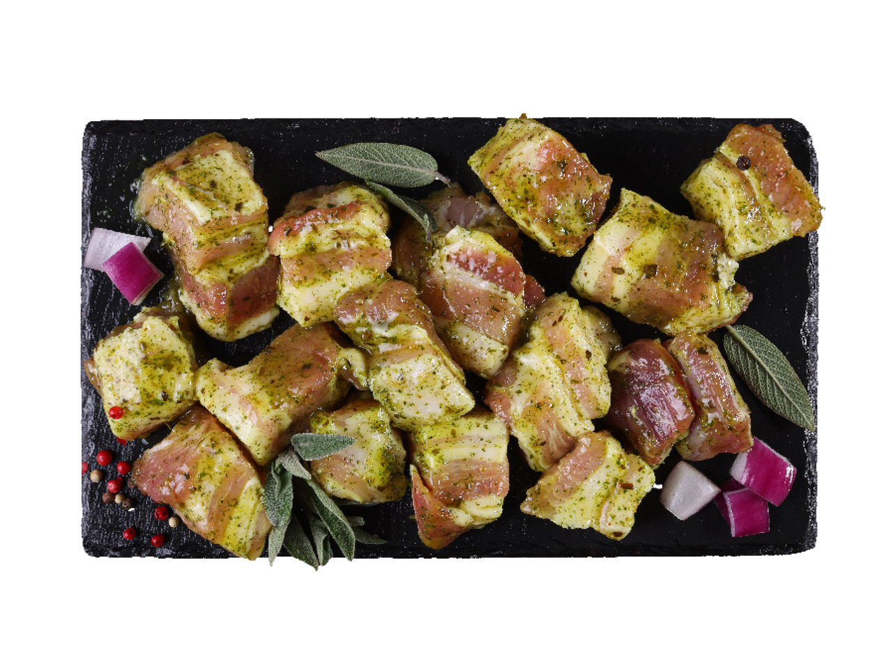 Marinirani komadi svinjskog mesa sa žalfijom i lukom na crnoj ploči.