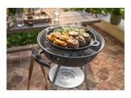 Charcoal barbecue with a cast iron pan cooking meat, potatoes, and green beans.