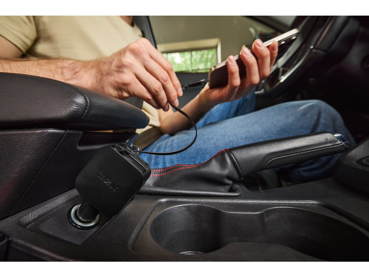 Man laadt een smartphone op in een auto met een autolader.