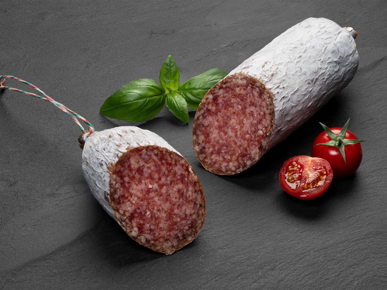 Szárazkolbász szeletek bazsalikommal és koktélparadicsommal.