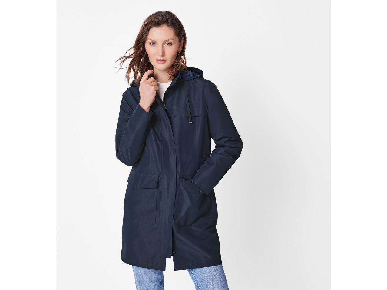A woman in a navy blue rain jacket and light wash jeans.