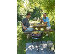 Homem e jovem a fazer um churrasco com espetadas de vegetais e peixe num jardim.