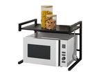 Microwave oven with a black metal shelf holding two glass jars of pasta and granola.