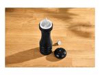 Black pepper mill with its top and adjustment knob removed, on a wooden surface.