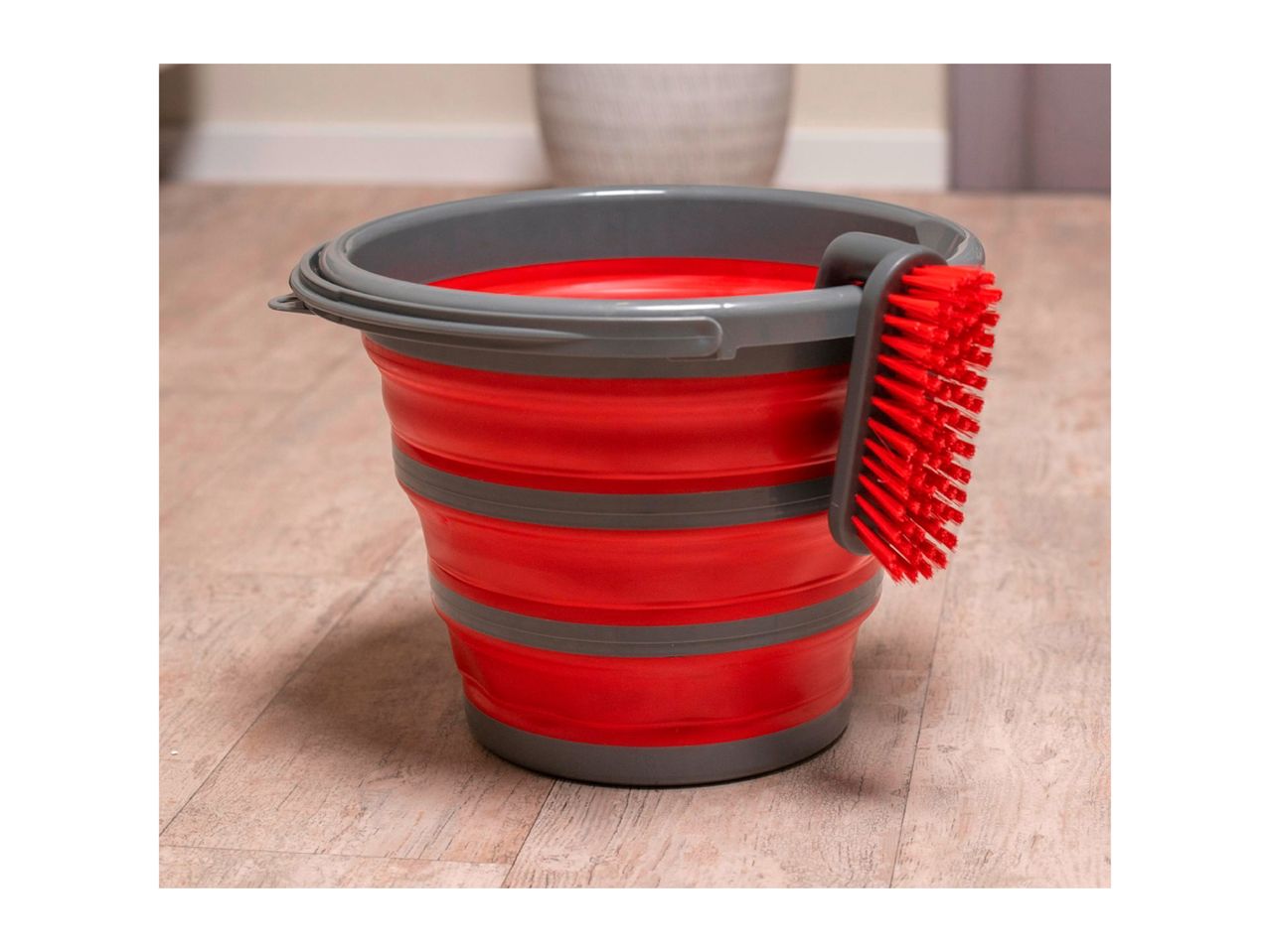 A red and gray collapsible silicone bucket with a red cleaning brush.