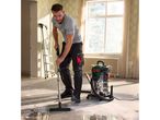 Man vacuuming a construction site with a wet and dry vacuum cleaner.