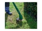 Person trimming grass with a green electric grass trimmer next to a hedge.