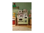 A children's play kitchen in light green, decorated for Christmas with string lights and a wooden tree.