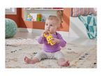 Baby in purple top and patterned pants playing with a yellow bear rattle on a rug.