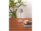 Candeeiro de mesa LED sem fios LIVARNO home numa mesa de madeira, com plantas ao fundo.