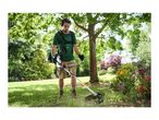 Man using a brush cutter in a garden, wearing safety glasses and ear protection.