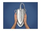 Hands holding a white and grey steam iron on a blue fabric surface.