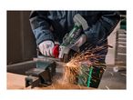 A person using a cordless angle grinder to cut metal clamped in a vise, creating sparks.