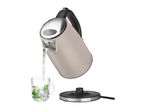 A beige electric kettle pours water into a glass, sitting on its base.