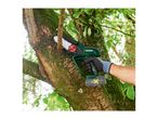 A person uses a mini chainsaw to cut a small branch from a moss-covered tree.