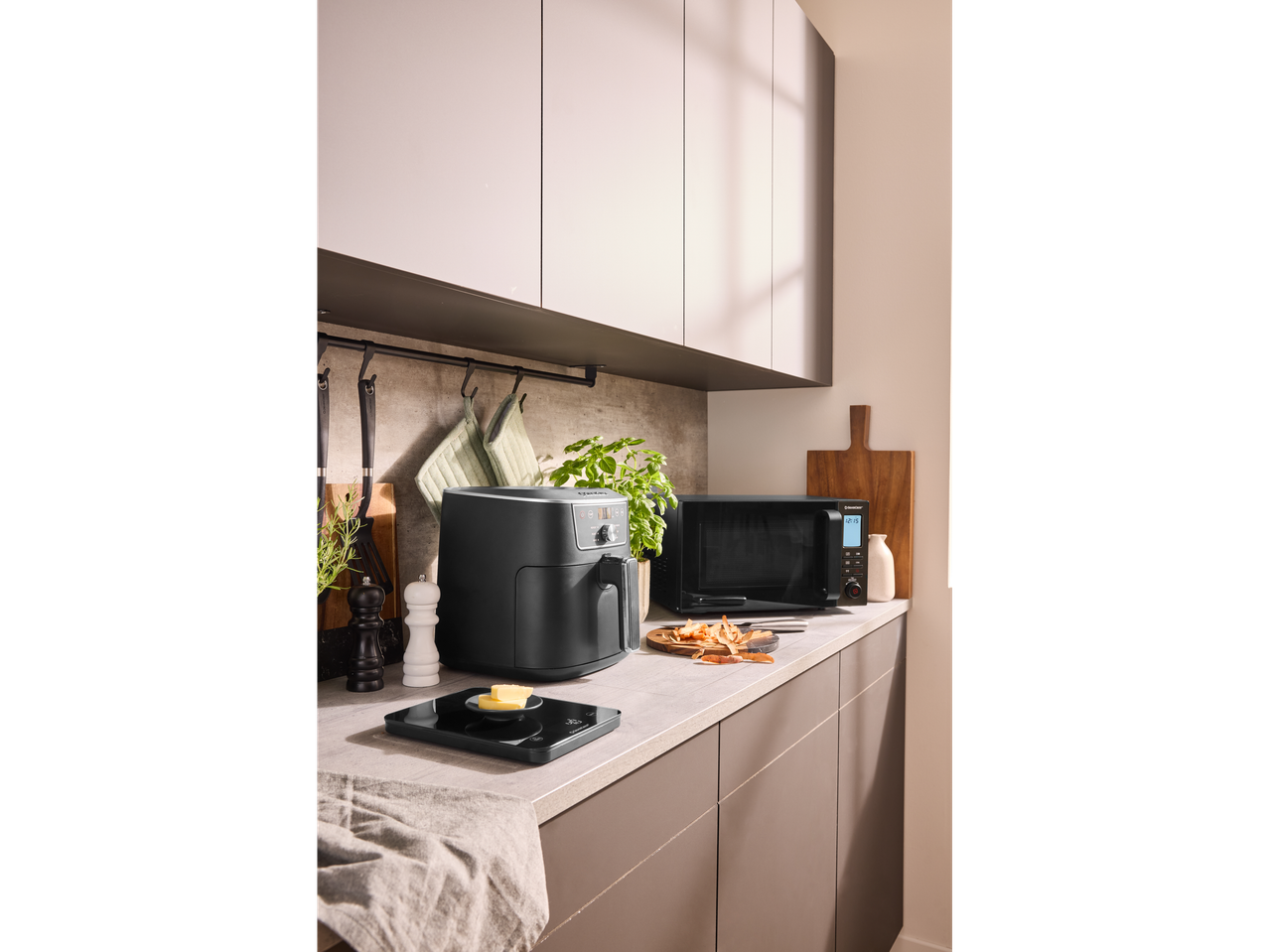 Un air fryer negru și un cuptor cu microunde pe un blat de bucătărie modern.