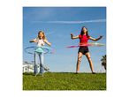 Two girls hula hooping on a sunny day in a park.
