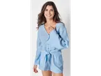O femeie zâmbește purtând un costum de vară albastru deschis.