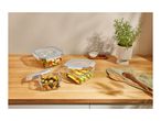 Glass food storage containers with various foods on a wooden countertop.