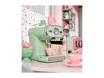 A mint green SilverCrest espresso machine brewing coffee in a pink cup in a retro kitchen.