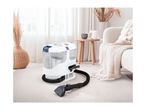 A portable carpet and upholstery cleaner on a rug in a bright living room.