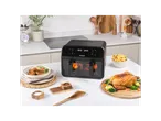 A black Salter air fryer on a kitchen counter with cooked chicken, fries, and salad.
