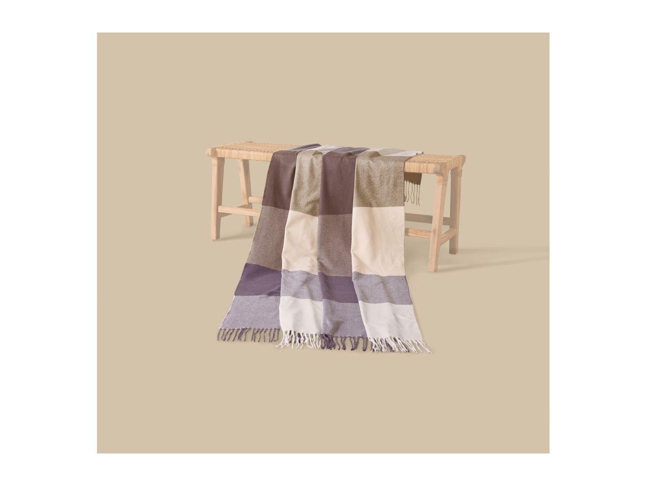 A striped throw blanket in shades of brown, beige, and purple draped over a wooden bench.