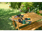 Serra de poda e corta-sebes numa mesa de madeira no jardim.