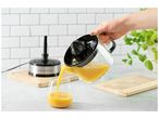 Jus d'orange frais versé d'un presse-agrumes électrique dans un verre.