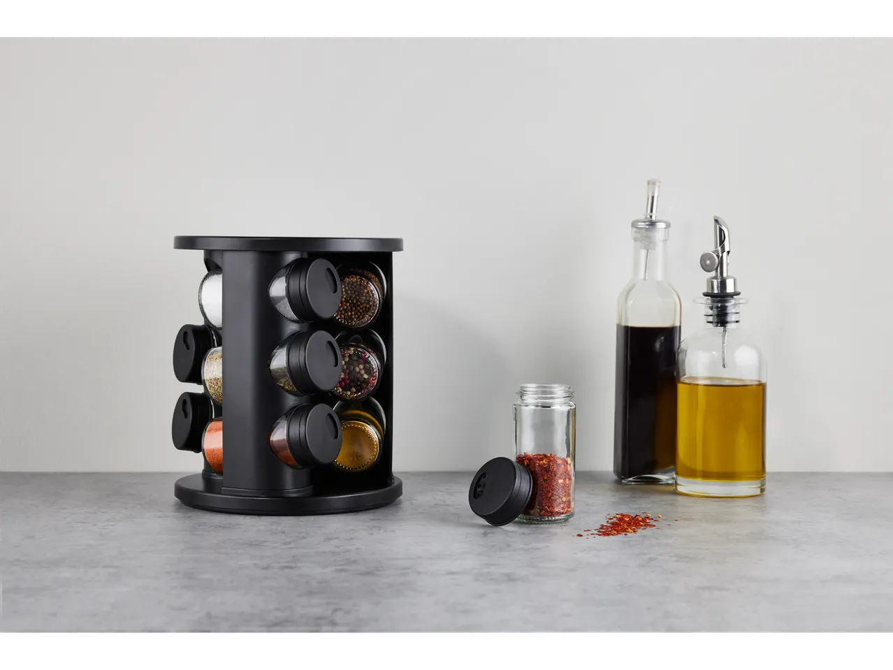 Suport de condimente cu condimente, ulei de măsline și oțet balsamic pe un blat.