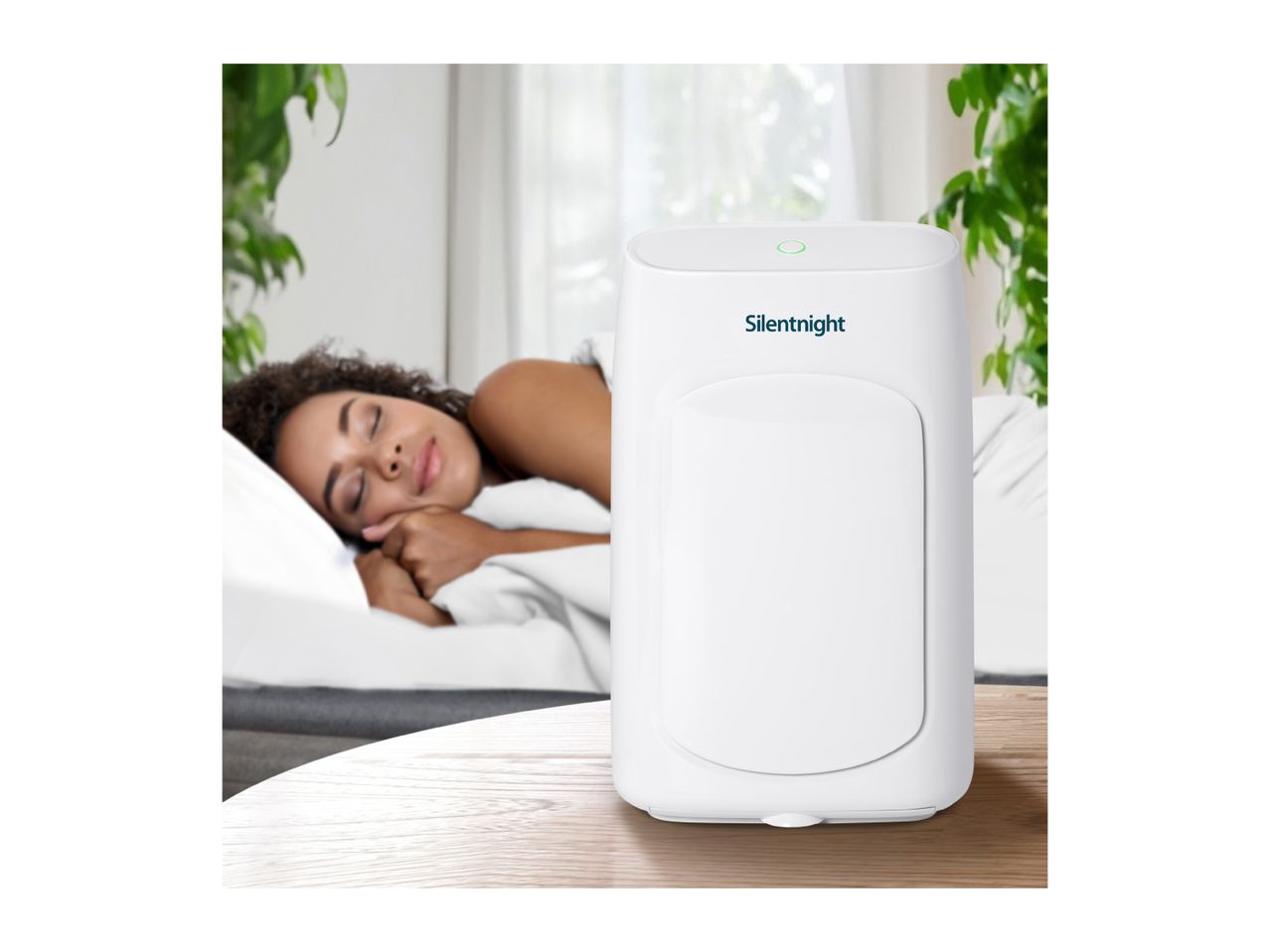 Silentnight air purifier on a wooden table with a sleeping person in the background