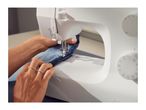 A person sewing denim fabric with a white sewing machine