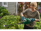 Woman in safety glasses and gloves trimming a hedge with a green Parkside® 450W Electric Hedge Trimmer.