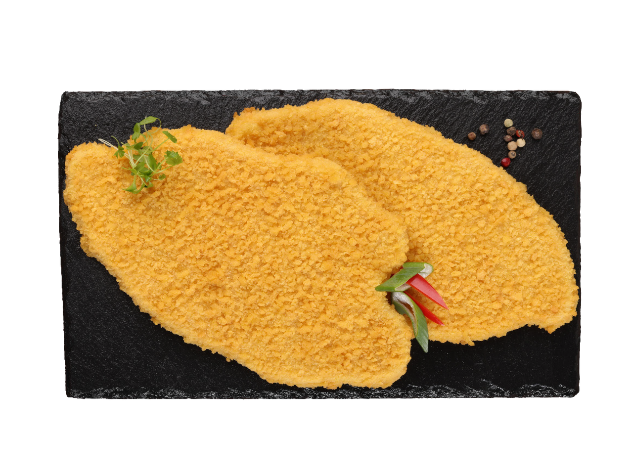 Dva pohovana pileća filea na crnoj ploči, ukrašena začinskim biljem i biberom.