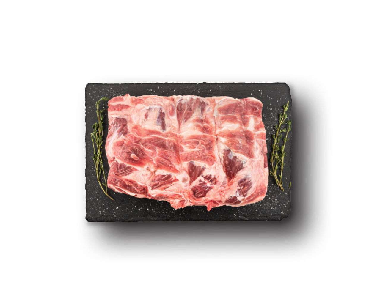 Jēlas cūkgaļas ribiņas uz melna dēlīša ar rozmarīnu un sāli.