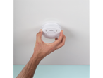 Ruka instalira beli Smartwares® detektor dima na beli plafon.