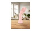 Pink handheld fan on a wooden table in a bright room.