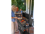 Woman grilling on a Grillmeister 6 Burner Gas Barbecue with family in the background.