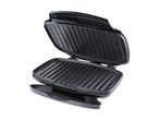 An open black electric grill or panini press with ridged plates and a drip tray.