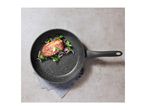 Frying pan with a cooked steak, red onions, and spinach on a grey surface.