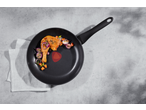 Chicken leg and vegetables in a frying pan on a concrete surface with a white cloth.