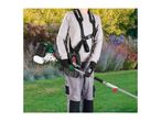 Person wearing a harness and gloves, holding a petrol multi-tool in a garden.