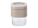 Square spice grinder with a clear base and a beige top with a visible grinding mechanism.