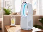 Egy elegáns, fehér Dyson ventilátor egy fa asztalon egy pohár limonádéval a háttérben.
